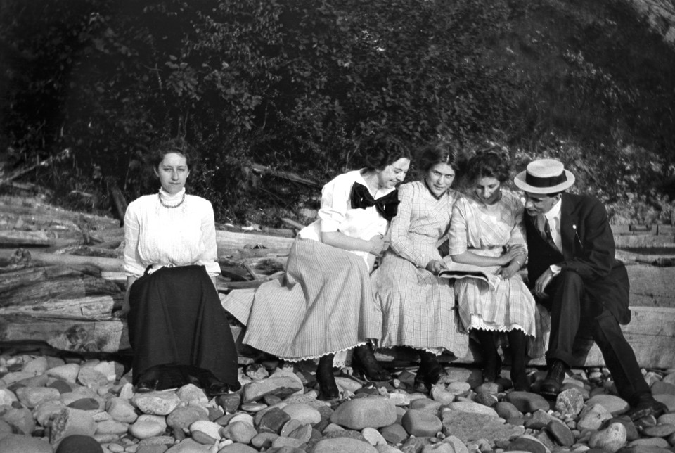 Social anxiety: it's not new!! ca. 1905 --- One women seems left out of the crowd while sitting on a log, ca. 1905 --- Image by © Kirn Vintage Stock/Corbis